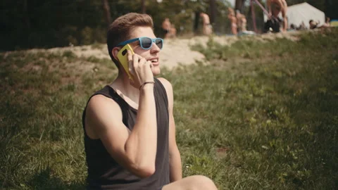 Young man talking on phone while sitting ona a grass. Stock Footage 94171590