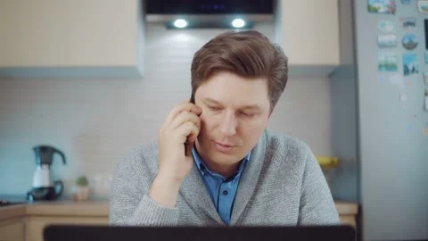Young man talking on the phone while working at the computer Stock Footage 148828373