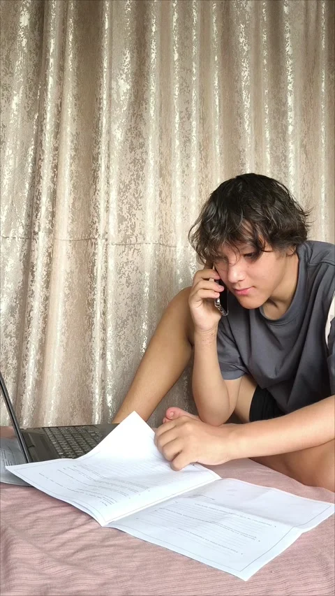 A young man is talking on the phone while working on a laptop Stockbeeldmateriaal 311653988