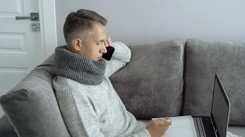Young man talking on the phone working at home during illness Stock Footage 110799069