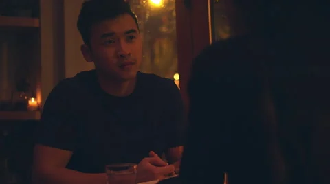 A young man talking on a romantic dinner date with city lights behind him Stock Footage 56886559