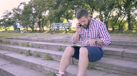 Young man talking by smartphone and browsing tablet. Slider and pan shot. Vídeo Stock 67243062