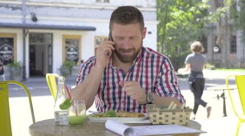 Young man talking by smartphone, during lunch. 動画素材 67604090