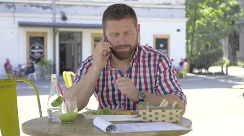 Young man talking by smartphone, during lunch, slider and pan shot. Video stock 67604280