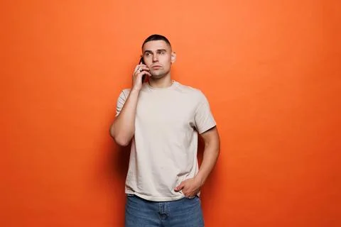 Young man talking on smartphone with expression isolated on orange background Stock Photos