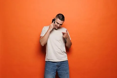 Young man talking on smartphone with expression isolated on orange background Stock Photos
