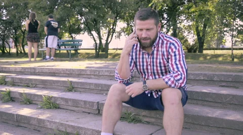 Young man talking by smartphone, sitting on stairs. Vídeo Stock 67239830