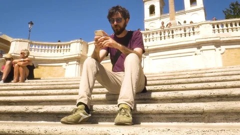 Young Man talking on smartphone sitting on steps in Rome Square Stock-Footage 77555710