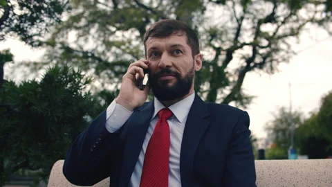 Young man talking on the smartphone while walking while sitting on a bench in a Stock Footage 165844423