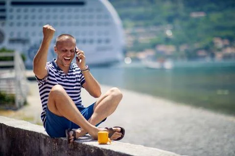 A young man is talking on the smartphone while taking a rest on the quay du.. Stock Photos