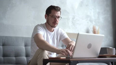 Young man talking on video calling at his laptop at home in the living room. Stock Footage 137999025