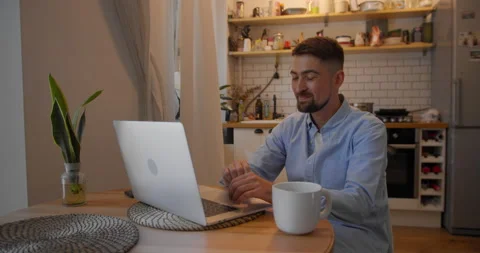 Young man talking on video calling at his laptop at home in the living room Stock Footage 157651677