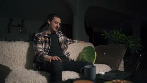 A young man is talking on a video link through a laptop and starts to dance 库存影片 170689464