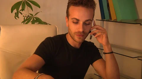 Young man talking with white mobile device/cellphone in office. Video stock 31616323