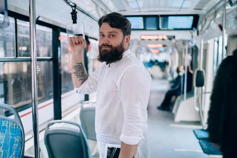 Young man with tattoo looking at camera in train Stock Photos