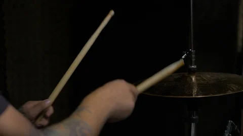Young man with tattoos playing a drum set in a dark room Stock Footage 94101343