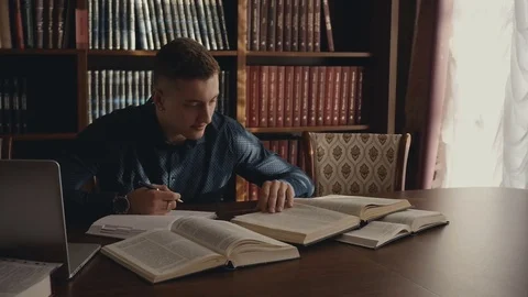 Young man teaches lessons using books and laptop Stock Footage 85246540