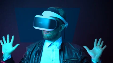 Young man testing for the first time virtual reality headset on dark background Stock Footage 121971668