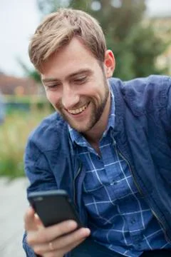 Young man text messaging with smartphone outdoors Stock Photos