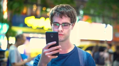 Young Man Texting and Reacting To Incomming Messages With People in Background Stock Footage 93439852