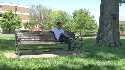 Young man texting on a bench outside Stock Footage 75675603