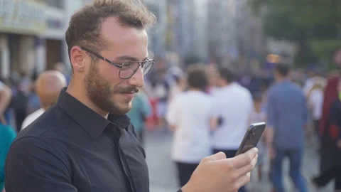 Young man texting on phone in crowded street. Video stock 213514969