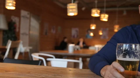 Young man texting on smartphone and drinking beer in cafe Stock Footage 67861341