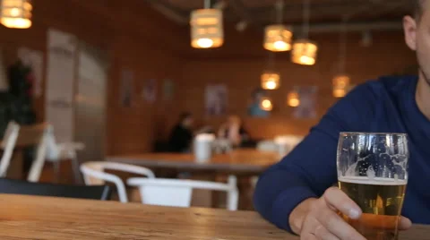 Young man texting on smartphone and drinking beer in cafe Stock Footage 67861361