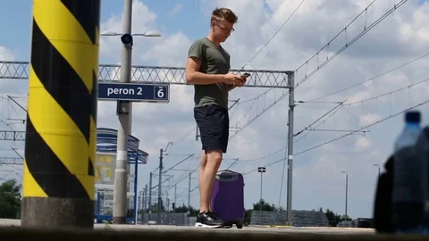 Young man texting on smartphone while waiting for his train on the platform Stock Footage 78652564