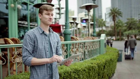 Young man is texting on a street by using his tablet pc Stock Footage 76140542