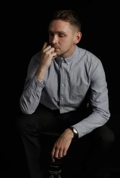 Young man thinking about something on black background Stock Photos