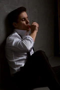 The young man is thinking about something drinking whiskey sitting on the flo Stock Photos