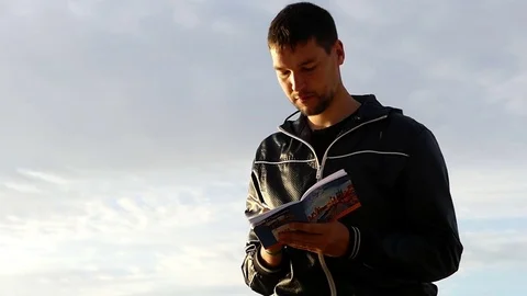 Young Man is Thinking and Putting Down Something Into His Notebook at a Stock Footage
