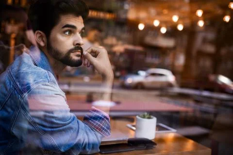 Young man thinking by the bar window Stock Photos