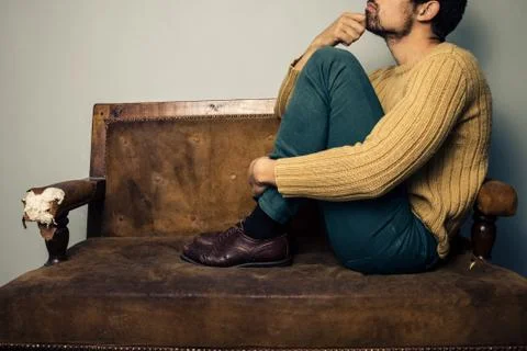 Young man thinking on the couch Photos