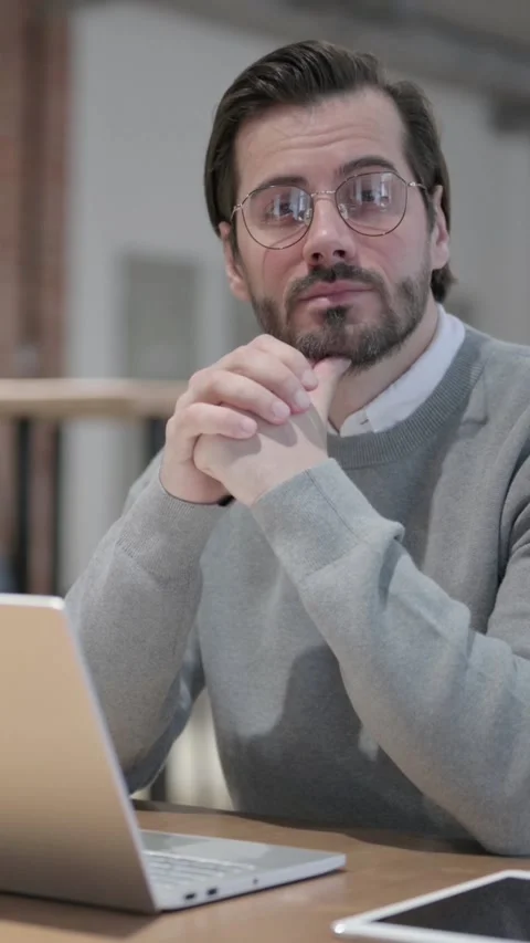 Young Man Thinking while Working on Laptop in Office, Vertical Video Stock Footage 339580536