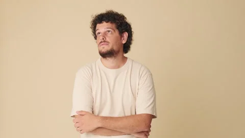 Young man thinks over his problem, remembering something isolated on beige 스톡 동영상 252502325