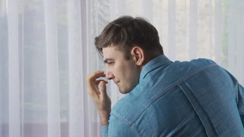 Young man thinks by the window,thoughtfully. Stock Footage 218920443