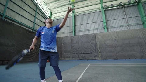 Young man throwing ball up in air and hitting serve on tennis court Stock Footage 221467403