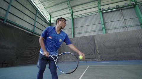 Young man throwing ball up in air and hitting serve on tennis court Stock Footage 221467433
