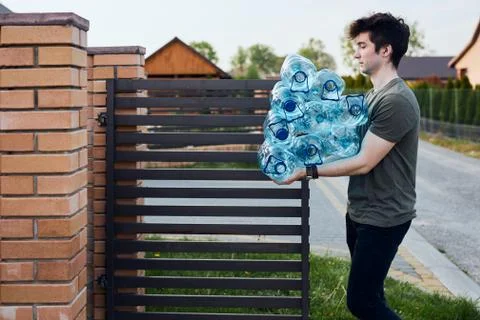 Young man throwing out empty used plastic water bottles into trash bin Stock Photos