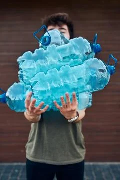 Young man throwing out empty used plastic water bottles into trash bin Foto stock