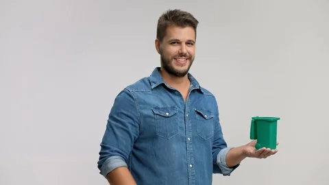 Young man throwing a piece of garbage in a small bin 스톡 동영상 77465308