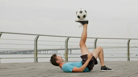 Young man throws and kicks ball lying on empty pathway Stock Footage 201694432