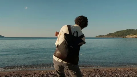 Young man throws flat small stone in sea in his leisure. Stock Footage 77523796