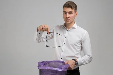 Young man throws glasses in trash isolated on white background Fotos Stock