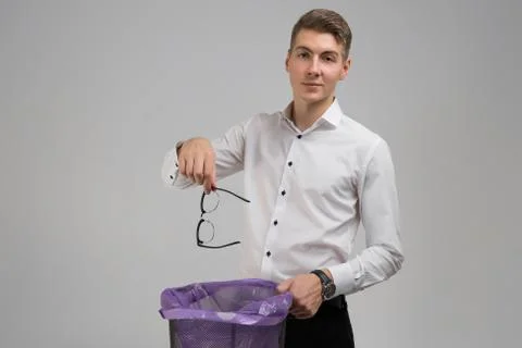 Young man throws glasses in trash isolated on white background Fotos Stock