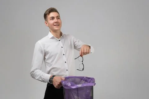 Young man throws glasses in trash isolated on white background Fotos Stock