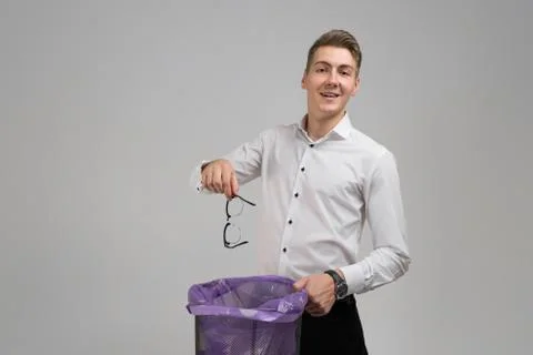 Young man throws glasses in trash isolated on white background Fotos Stock