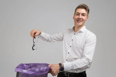 Young man throws glasses in trash isolated on white background Fotos Stock